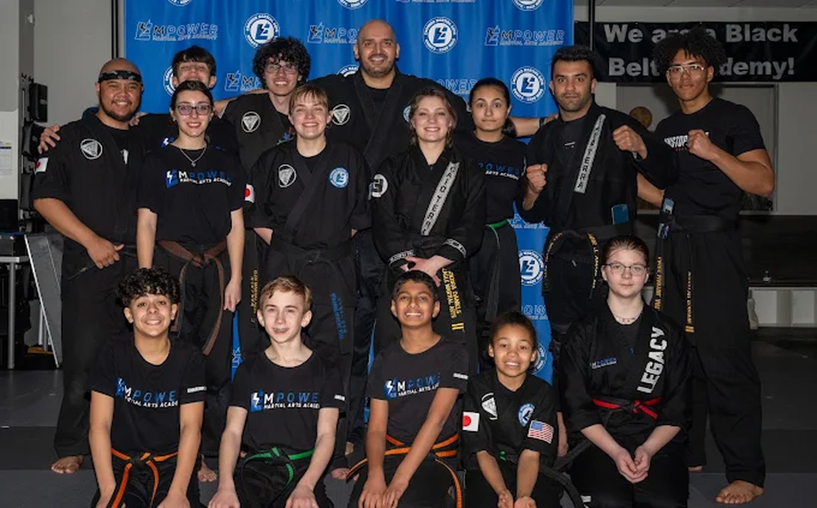 Empower Martial Arts Academy black belt team photo — instructors and students together in the dojo